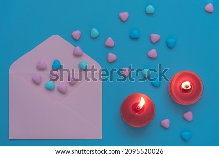 Delicate non-contrasting picture, view from above. Valentine's Day card, wedding or birthday card. Red candles are burning. Pink envelope, multi-colored hearts. A symbol of love and tenderness. Soft
