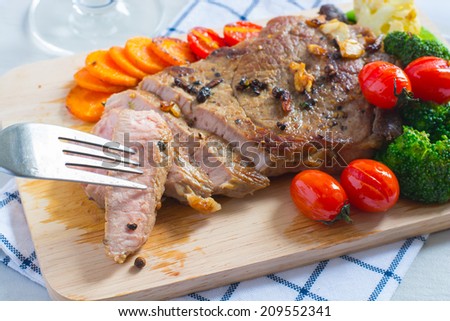 grilled fillet steak served with tomatoes and roast vegetables on an wooden board