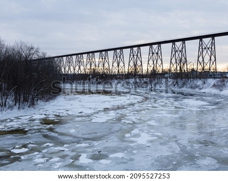 View of the 1908 railway trestle bridge over the partly frozen Cap-Rouge River seen during a cloudy winter sunrise, Cap-Rouge area, Quebec City, Quebec, Canada Royalty-Free Stock Photo #2095527253