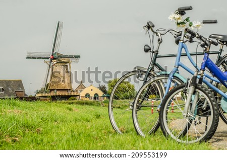 Family with bicycles on the picnic in a Dutch village meadow with windmill on the background, focus on windmill Royalty-Free Stock Photo #209553199