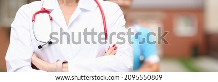Doctors veterinarians stand confidently with folded hands on background of farm. Medical services concept
