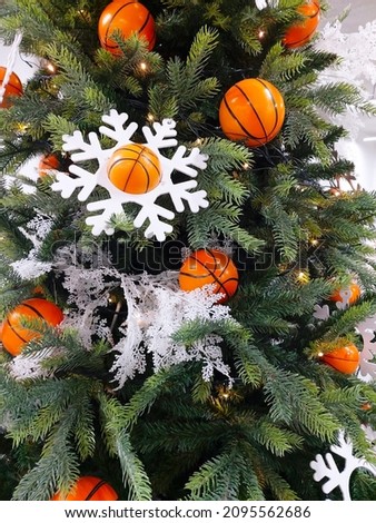  Christmas artificial green Christmas tree decorated in a sporty style. Toys in the form of a sports basketball, stars, snowflakes, garlands. Original Christmas holiday background.