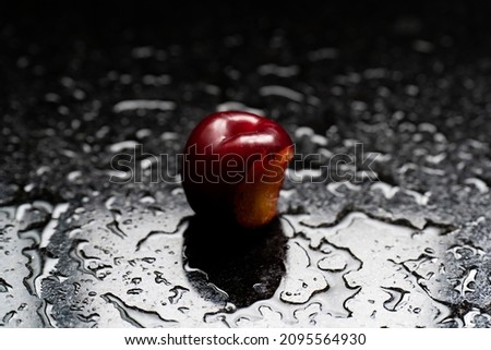 Fresh organic red plums on top of black marble with water bubbles