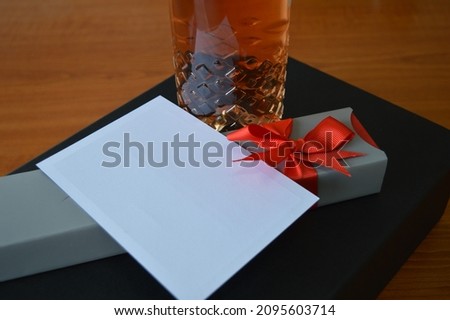 a luxury gift with a bottle of good wine, a beautiful chocolate bar with a red bow and a blank white message card. A very nice sign of attention and love