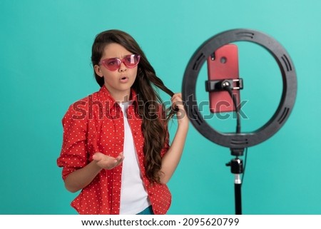 serious kid talking on camera shows her long hair blogging online with selfie led, childhood.