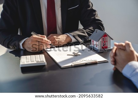 Real estate agent is reviewing the documents before handing over the house and keys to the customer after the contract is signed. Concept of mortgage, lease, purchase and home insurance.