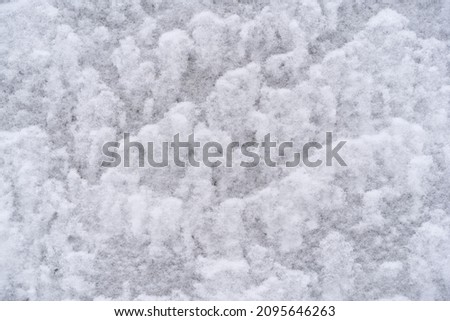 texture of white snow on the wall outside in winter,
lies in waves