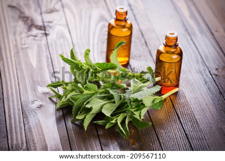 Fresh mint and aroma oil with peppermint  on wooden background. Selective focus.
