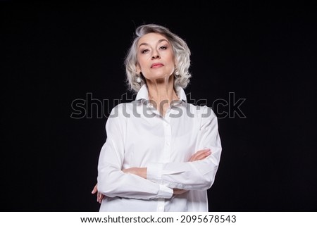 Portrait of a domineering, arrogant mature woman looking down and standing with her arms crossed isolated on a black background Royalty-Free Stock Photo #2095678543