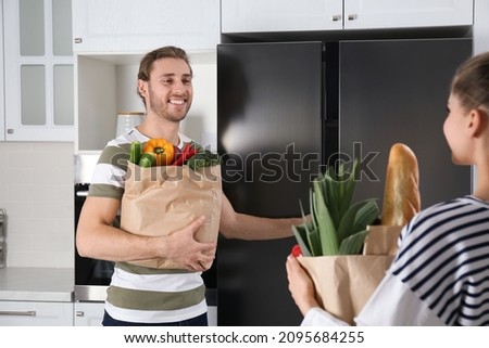 Couple with fresh products near refrigerator in kitchen