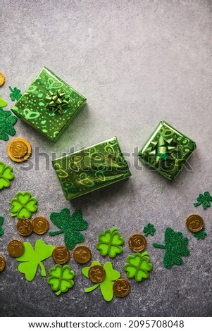 Decorative clover leaves, green gifts box, coins on stone background, flat lay. St. Patrick's Day celebration with  card Happy Saint Patricks Day