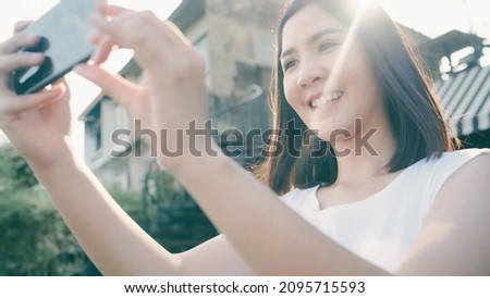 Young Asian woman blogger tourist use smartphone take photo in front of port river feel happy joyful with beautiful sun light travel at cafe city town , Lifestyle tourist travel holiday concept.