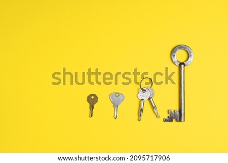 Door keys of different shapes arranged in a row against a bright yellow background. Flat lay concept.
