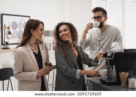 African American woman talking with colleagues while using modern coffee machine in office Royalty-Free Stock Photo #2095729609
