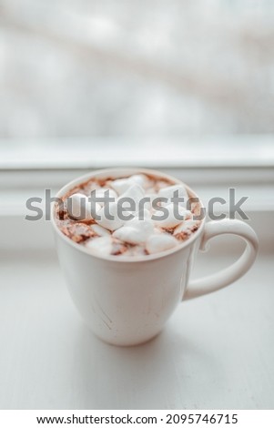 Cocoa with white marshmallows on the windowsill and defocused background