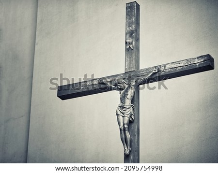 Catholic cross with crucified  Jesus Christ statue over rough backgraund. Crucifixion. Jesus Christ statue on wood cross. Religion and faith concept. Black and white toned picture