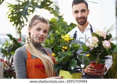 Cute florist workers hold flowers in pots, professional consultants ready to help with choice Royalty-Free Stock Photo #2095759984
