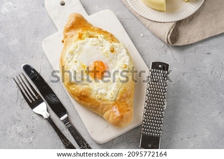 Traditional georgian dish of cheese-filled bread adjarian khachapuri with fried egg on a marble board