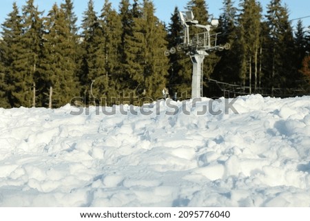 Snow against ski lift and forest, selective focus