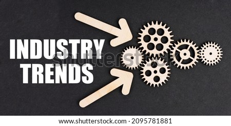 Industrial concept. On the black surface, arrows, gears and an inscription - INDUSTRY TRENDS