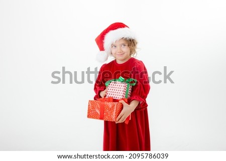 a cute little girl in a Santa Claus hat holds gifts isolated on a white background
