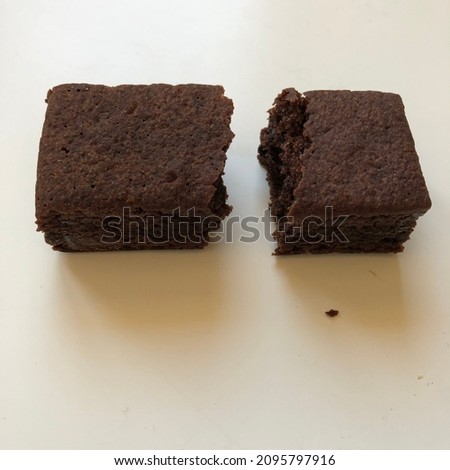 Picture of brownie cake with crumbs divided into rectangular halves with white background