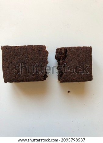 Picture of brownie cake with crumbs divided into rectangular halves with white background