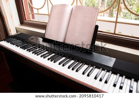 Electric piano with empty sheet music near the window right side view