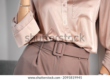 Women's classic business style of clothing. Palazzo trousers with a wide belt and a silk blouse. Powdery pink color. A combination of shades of color in clothing. Royalty-Free Stock Photo #2095819945