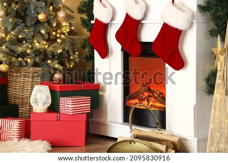 Christmas gifts near modern fireplace with socks in room