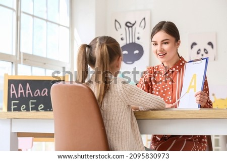 Speech therapist working with cute girl in clinic Royalty-Free Stock Photo #2095830973