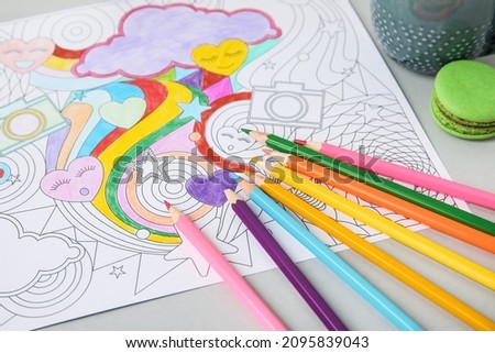 Coloring picture and pencils on table, closeup
