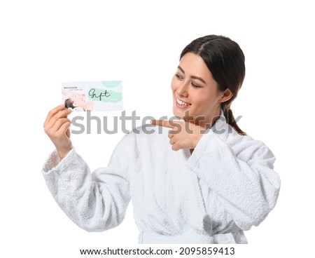 Young Asian woman pointing at gift voucher for massage on white background