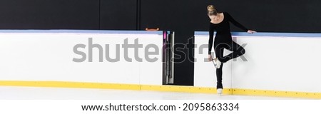 full length of figure skater in black bodysuit checking blade on ice skates near frozen ice arena, banner