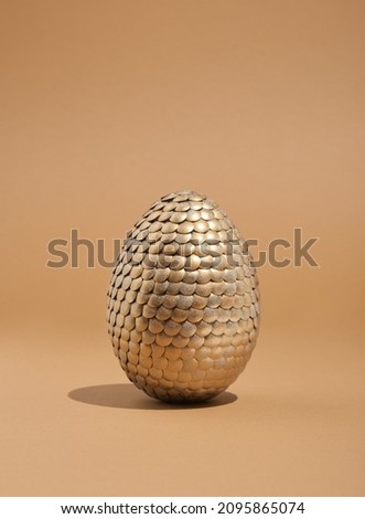 Beautiful golden shiny egg on pastel beige background. Idea of Easter, celebration, religion.