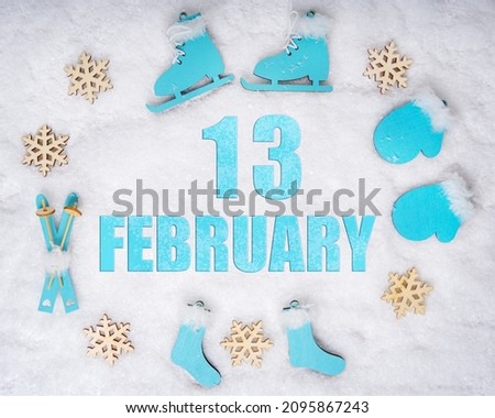 February 13th. Sports set with blue wooden skates, skis, sledges and snowflakes and a calendar date. Day 13 of month. Winter sports concept. Winter month, day of the year concept.