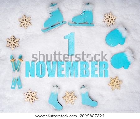 November 1st. Sports set with blue wooden skates, skis, sledges and snowflakes and a calendar date. Day 1 of month. Winter sports concept. Winter month, day of the year concept.
