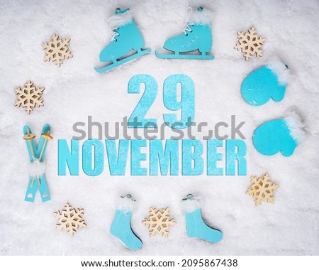 November 29th. Sports set with blue wooden skates, skis, sledges and snowflakes and a calendar date. Day 29 of month. Winter sports concept. Winter month, day of the year concept.