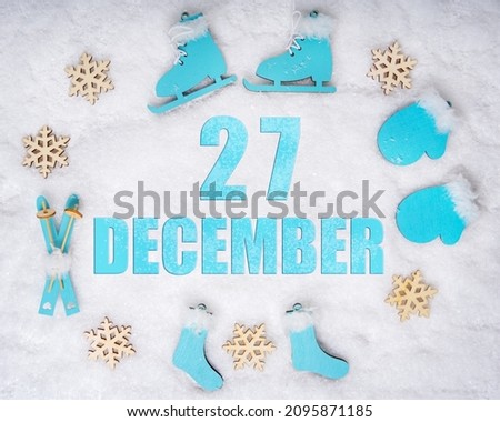 December 27th. Sports set with blue wooden skates, skis, sledges and snowflakes and a calendar date. Day 27 of month. Winter sports concept. Winter month, day of the year concept.