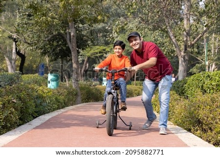 Father teaching son riding bicycle at park
 Royalty-Free Stock Photo #2095882771