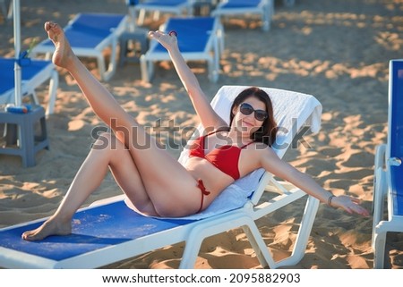 oung woman in red bikini lies at the sunbed enjoying her vacation