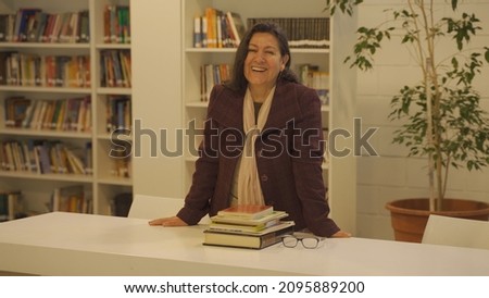 Learned experienced Argentinian teacher smiling at a library