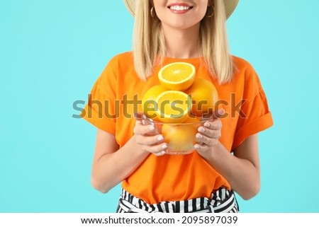 Beautiful young woman with oranges on color background