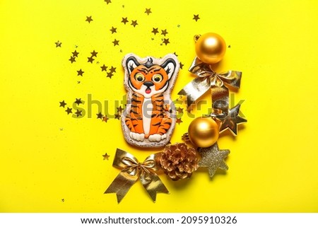 Beautiful Christmas composition with decorations and tasty cookie in shape of tiger on yellow background