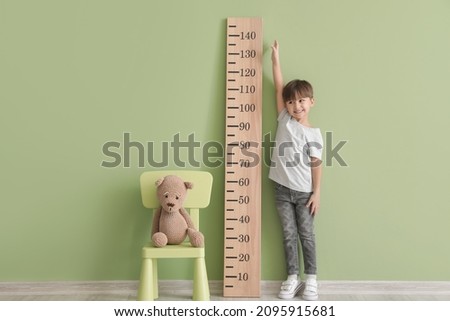 Little boy measuring height near color wall Royalty-Free Stock Photo #2095915681