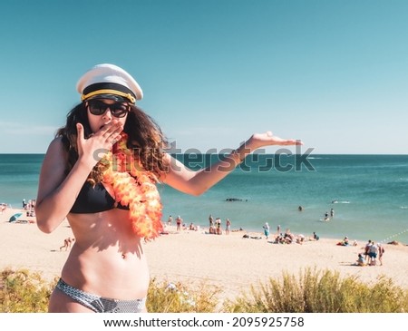 Young brunette woman in a Santa Claus hat and bikini in the shock of what she saw against the backdrop of the sea coast. copy space. sailor girl