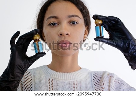 African girl holds small bottles in black gloves on a white background. Isolated. High quality photo