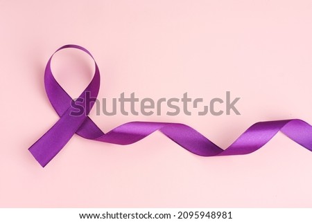 International symbol of Cancer Awareness Month. Close up of satin purple ribbon awareness on pink background with copy space. Women's health care and medical concept.