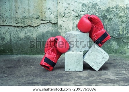 Sport mock up concrete cube empty podium surrounded with red boxing gloves on grunge cement background. Abstract banner or minimal scene for fitness product presentation.