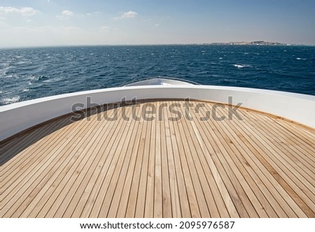 Teak bow deck of a large luxury motor yacht out at sea with a tropical ocean view background Royalty-Free Stock Photo #2095976587